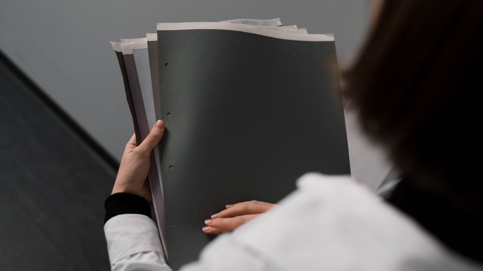 Une gérante de petite entreprise classe des dossiers et des documents papier sur son bureau, téléphone à la main.